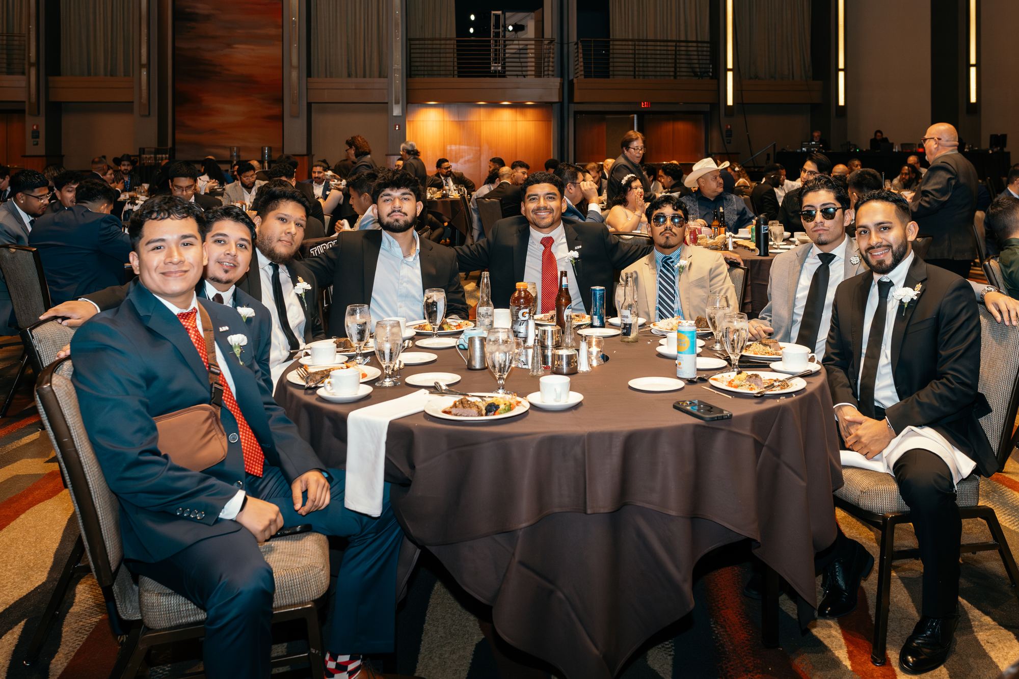 Nine brothers in suits seated around a banquet table at a formal dinner.